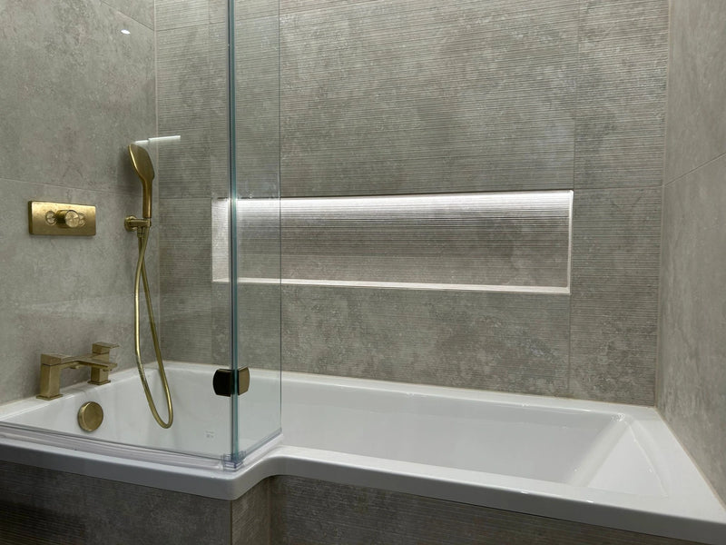 Modern bathroom with a shower enclosure, white bathtub, and gold fixtures.