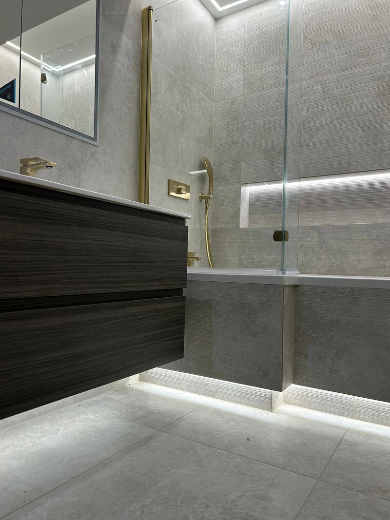Modern bathroom with glass shower enclosure, dark wooden vanity, and gray tiles.