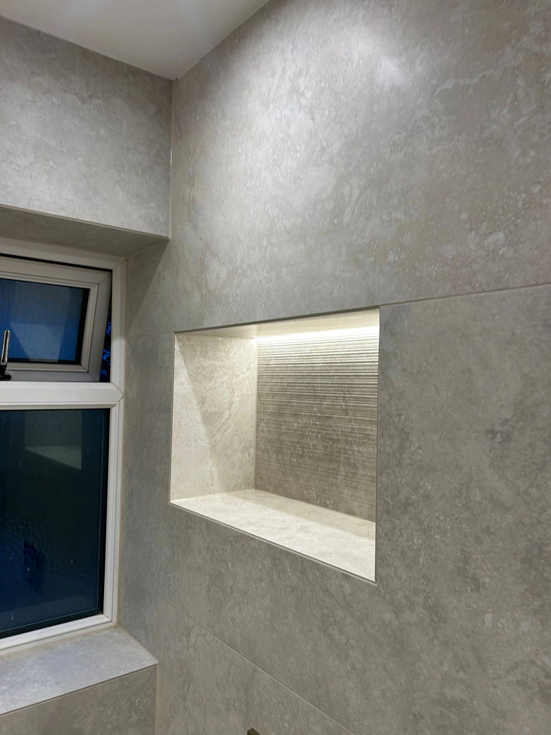 Gray tiled wall with a niche and window in a bathroom setting