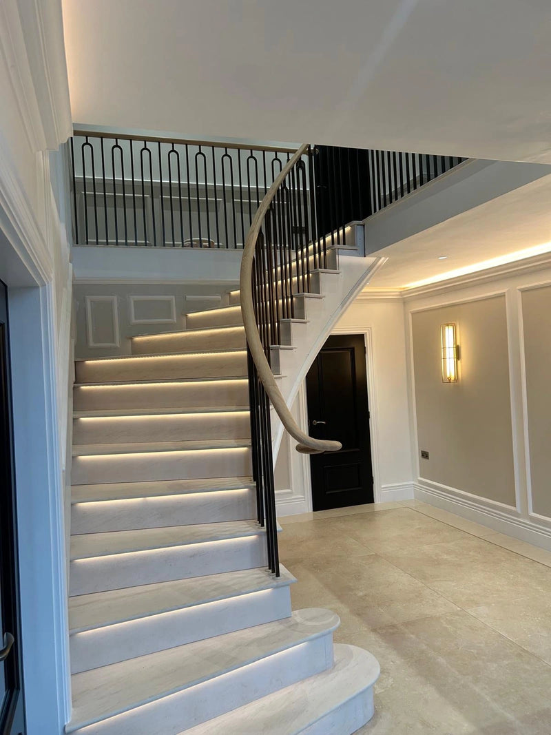 Modern staircase with white steps and black railing in a well-lit hallway.
