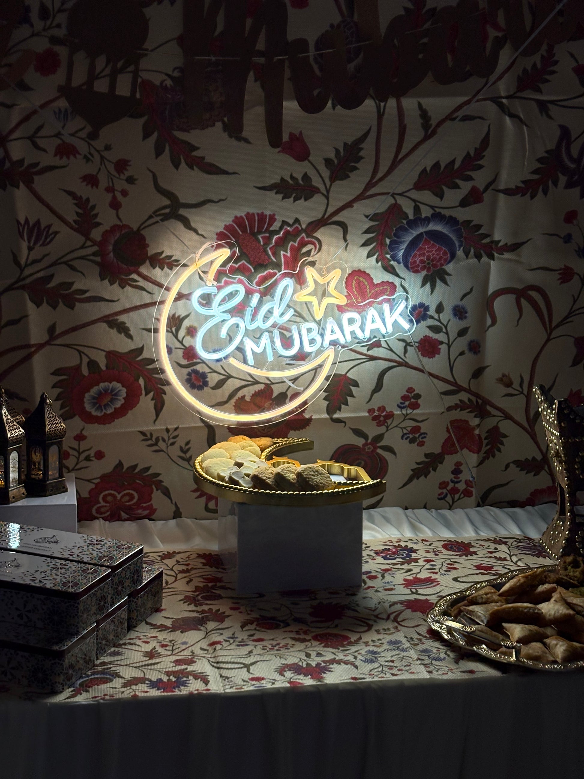 Eid Mubarak Neon sign on a floral wallpapered wall.