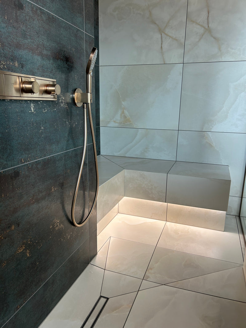 Modern shower setup with handheld shower head and control panel on a tiled wall.