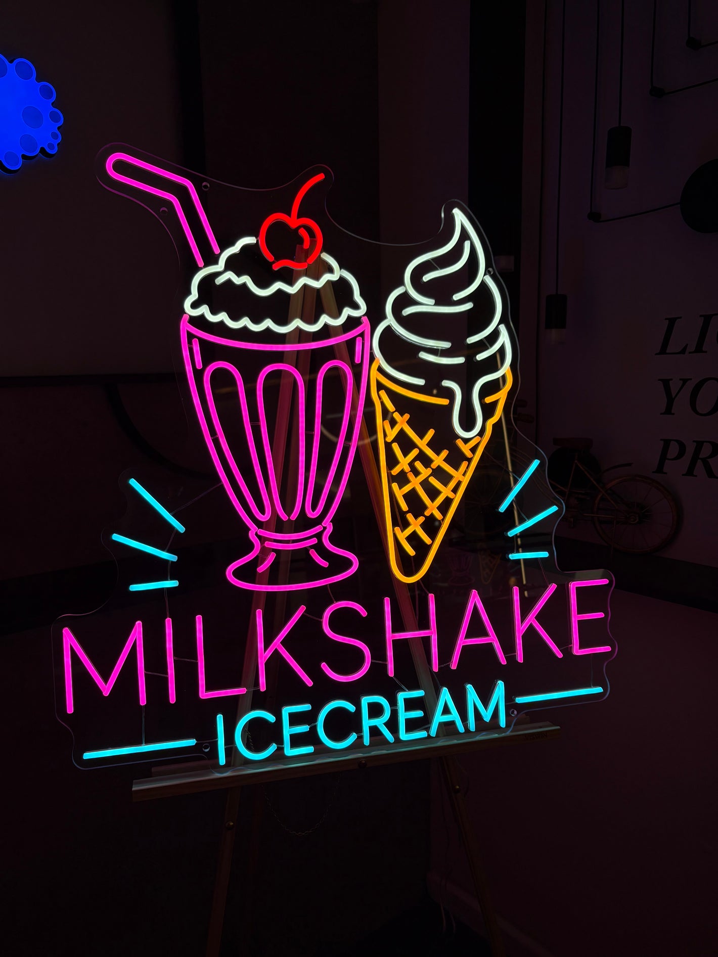 Neon sign featuring a milkshake and ice cream cone with colorful text on a dark background.