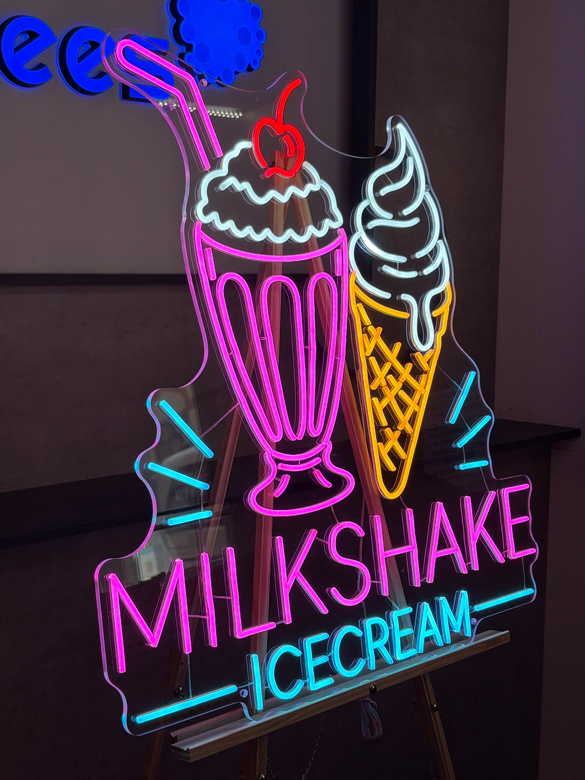 Neon sign with ice cream cone and text on a dark background