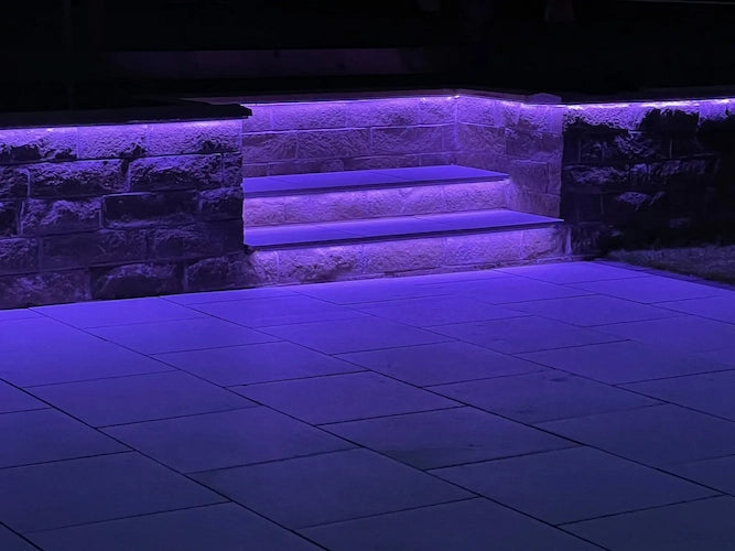 Stairs with purple LED lighting on a stone wall at night
