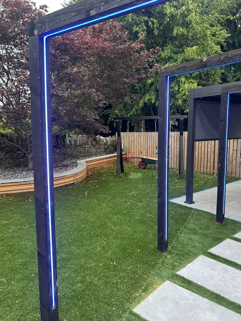 Garden with a blue LED light arch, grass, and a wooden fence.