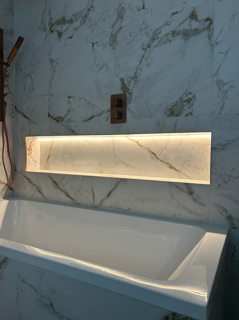 Rectangular light fixture on a marble wall above a white sink.