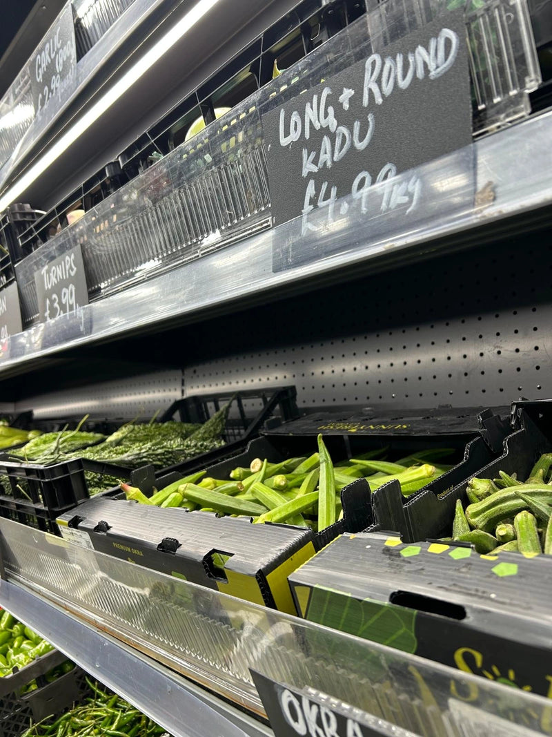 Grocery store produce section with green beans and price signs.
