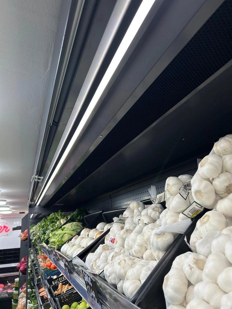 Display of garlic in a grocery store with refrigerated shelves.