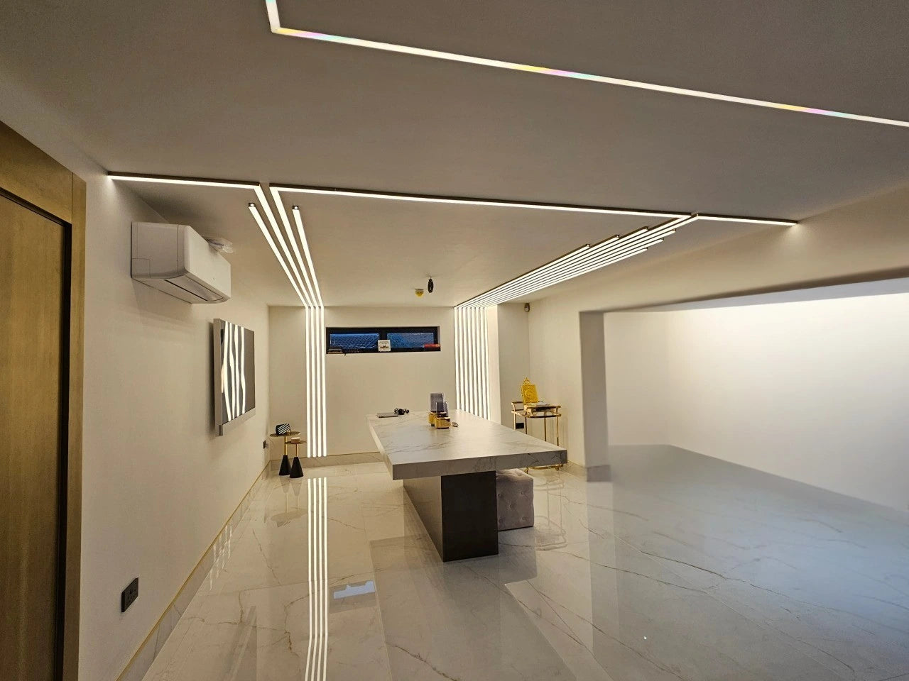 Modern office interior with a long desk, chairs, and decorative elements complimented by artistic interior LED Lighting.