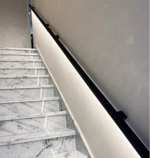 Marble staircase with black handrail against a neutral wall